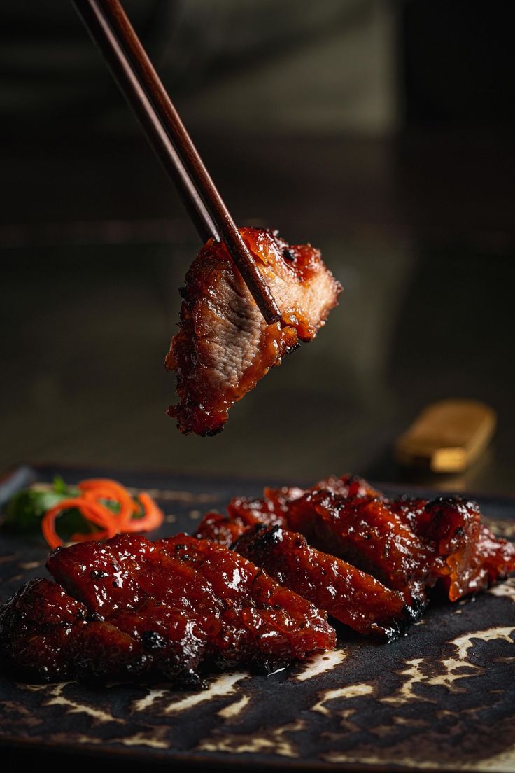 chopsticks holding up meat on top of a cutting board