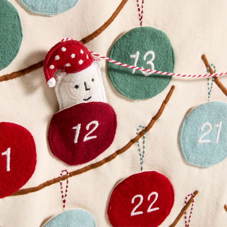 a felt christmas ornament hanging on a tree branch with numbered ornaments around it