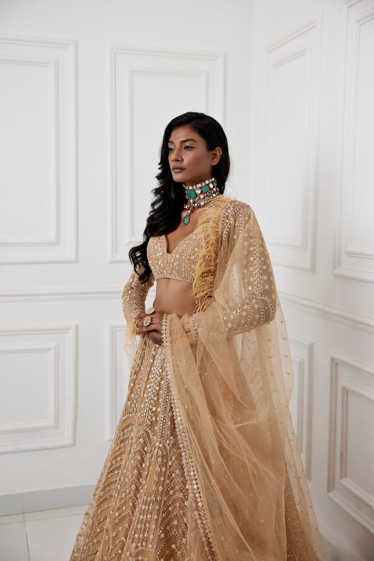 Gold mirror and zardozi embroidered tulle lehenga paired embroidered full sleeve blouse with feather detailing and tulle dupatta with embroidery and feather border.From Chamee and Palak's The Romantics collection.DELIVERY TIMEPlease allow 8-12 weeks for your outfit to arrive.FABRIC DETAILSOrganza, Silk, NetProfessional cleaning only. Festive Designer Hand Embellished Choli, Bollywood Style Hand Embellished Tissue Silk Sets, Glamorous Festive Choli With Intricate Embroidery, Hand Embellished Tissue Silk Sets For Reception, Festive Glamorous Hand Embellished Dupatta, Elegant Net Sharara With Mirror Work, Bollywood Style Hand Embellished Saree Sets, Glamorous Designer Lehenga With Intricate Embroidery, Glamorous Designer Lehenga For Eid