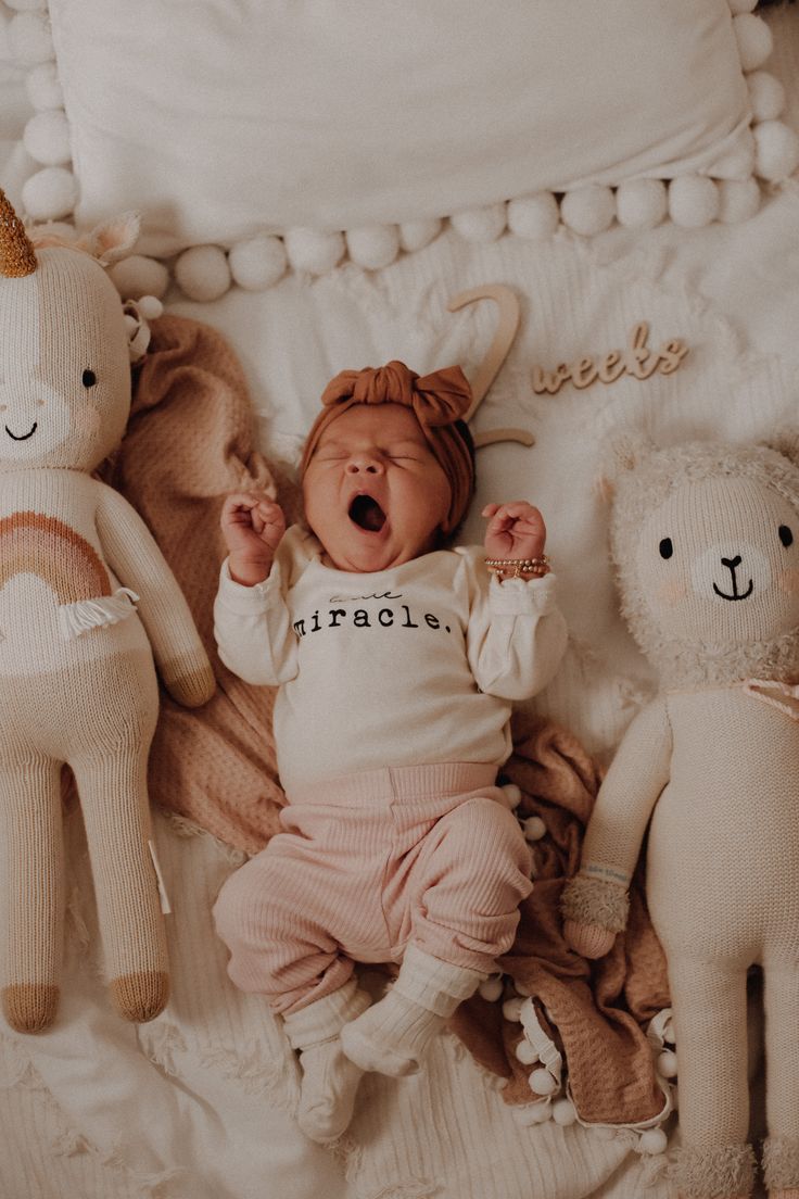 a baby is laying next to stuffed animals