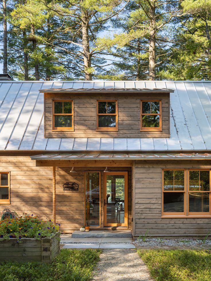 a small wooden house in the woods with metal roof and shingles on it's sides