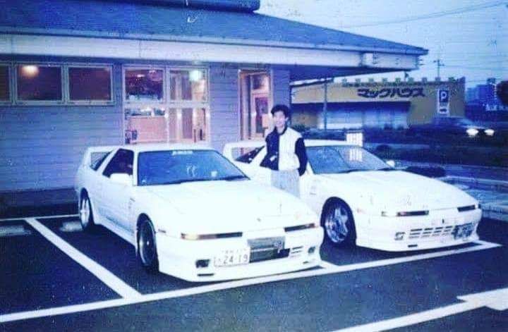 two white sports cars parked in front of a building with a man standing next to them