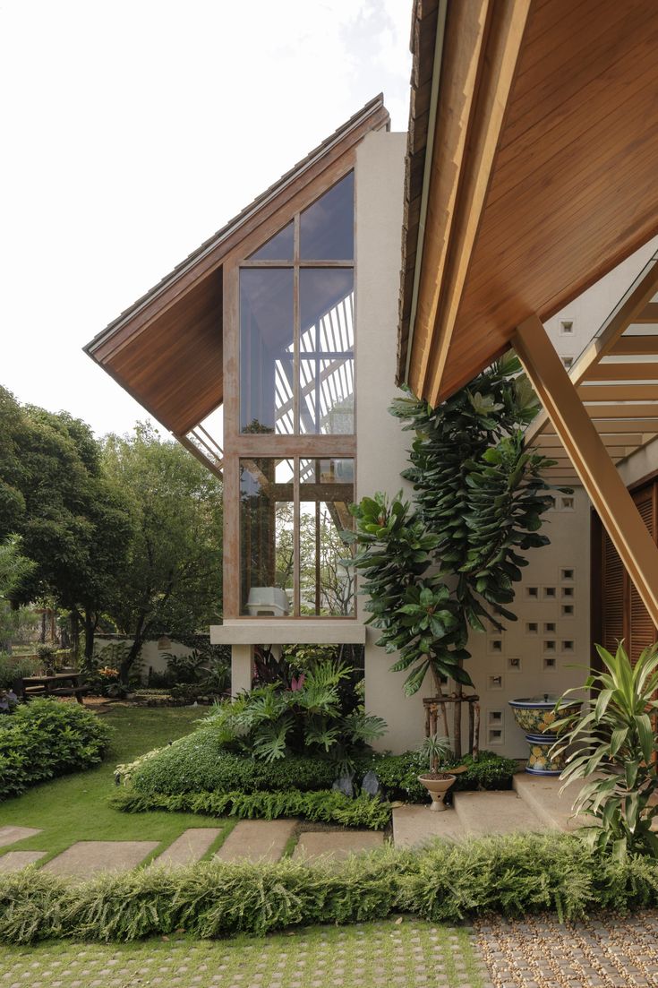 the house is surrounded by greenery and stone steps that lead up to the second floor