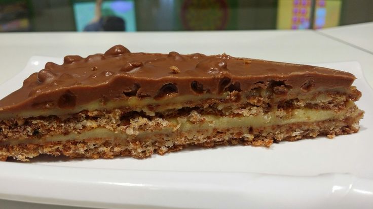 a piece of cake on a white plate with chocolate frosting and pecans in the middle