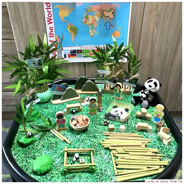 a table topped with lots of fake plants and animals on top of green grass covered ground