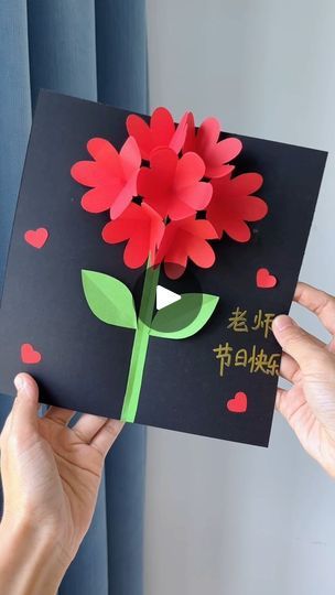 someone is holding up a card with paper flowers on it and writing in the chinese language