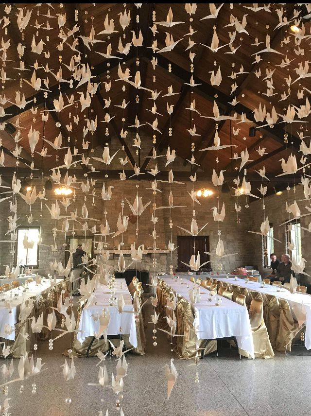 several tables with white tablecloths and paper birds hanging from the ceiling