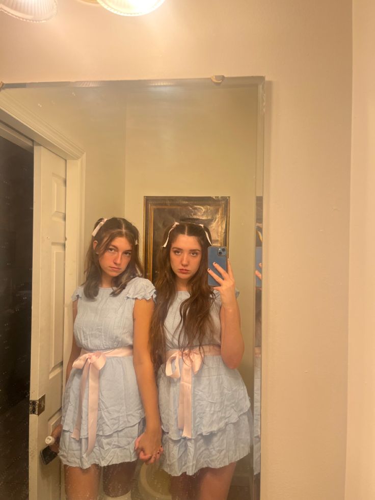 two girls are standing in front of a mirror