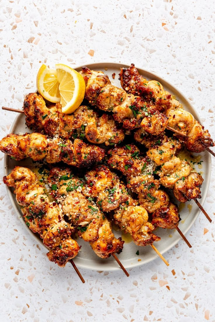 chicken skewers with lemon and parsley on a plate