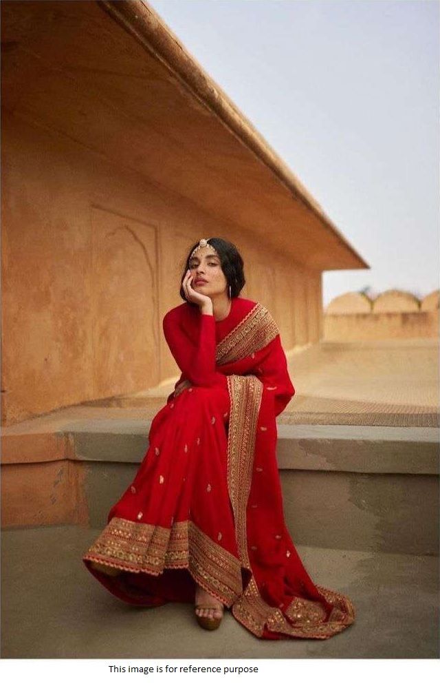 a woman in a red and gold dress sitting on steps with her hand to her face