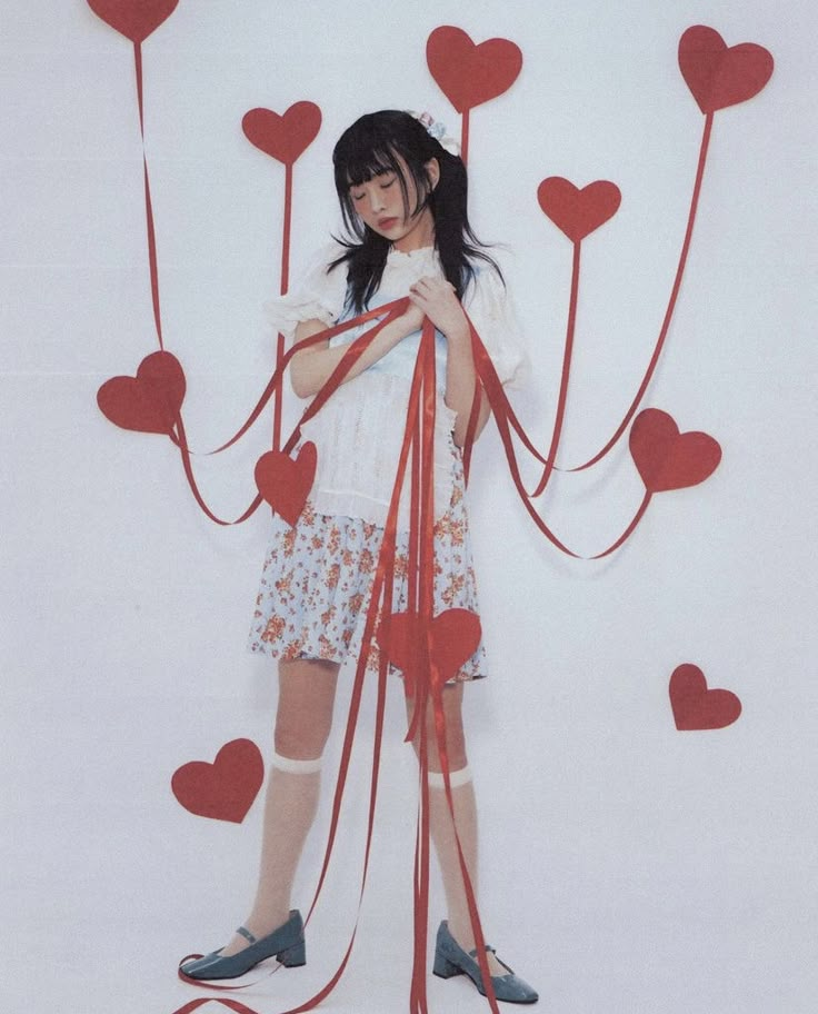 a woman standing in front of a wall with red hearts on it's sides