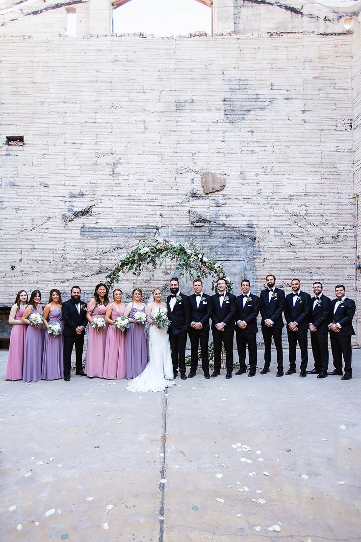 a group of people standing next to each other in front of a brick wall with an arch