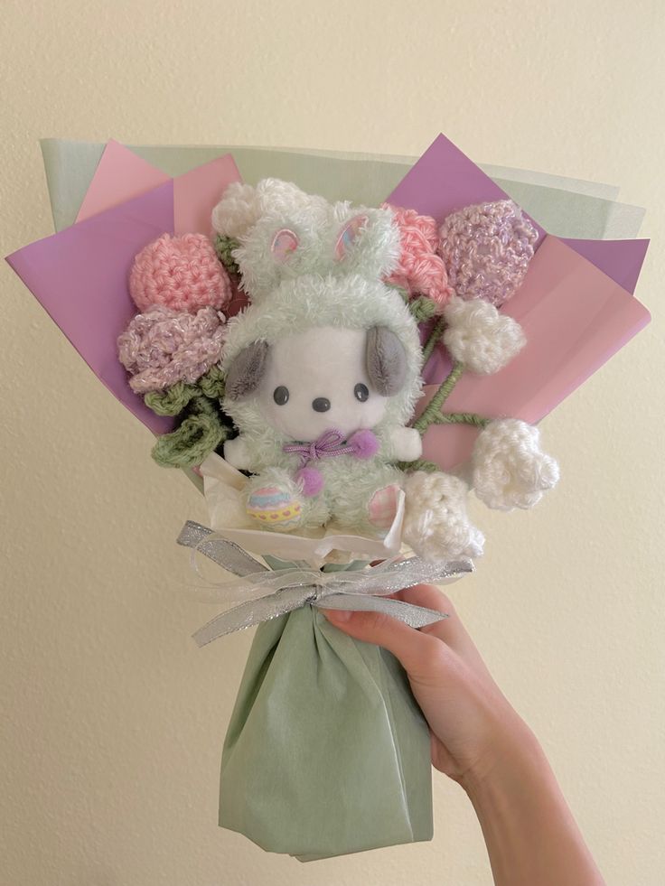 a person holding a stuffed animal in a bag with flowers on it's head