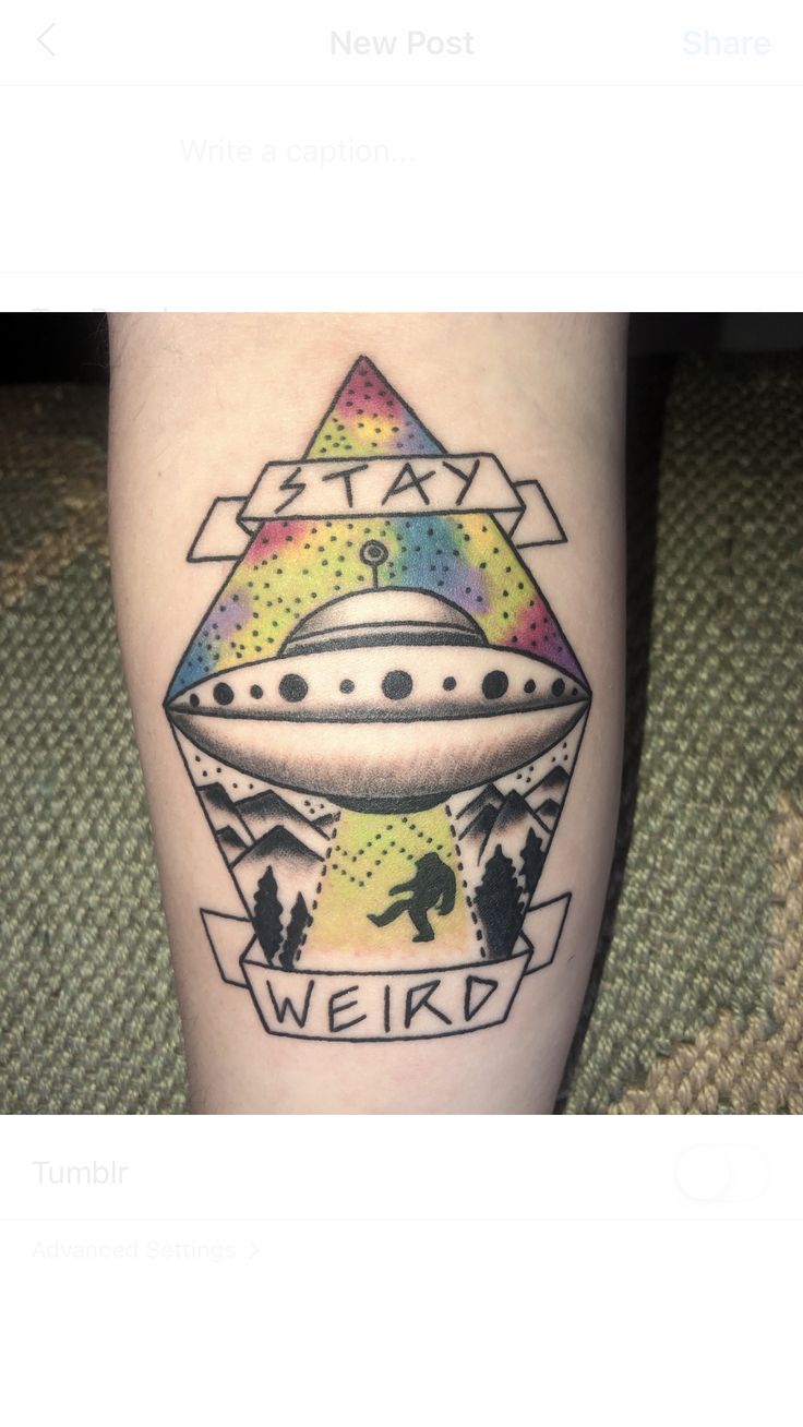 a tattoo on the leg of a person with an alien ship and stars above it