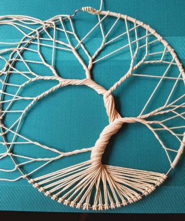 a piece of art that is made out of string and yarn on a blue surface