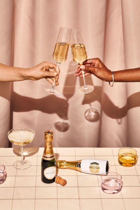 two people toasting with wine glasses and champagne bottles on a table next to other drinks