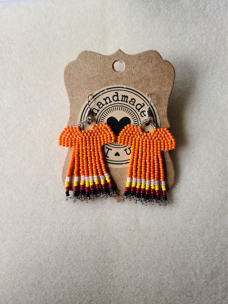 an orange and black beaded earring on a card