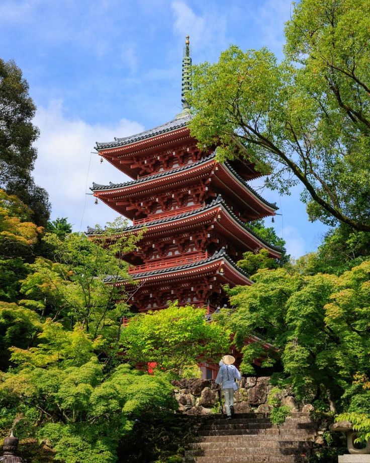 a tall red pagoda surrounded by trees and bushes