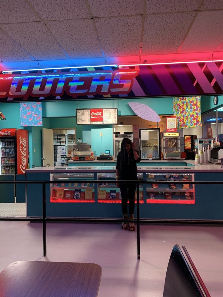 a woman standing in front of a counter at a fast food restaurant with neon lights