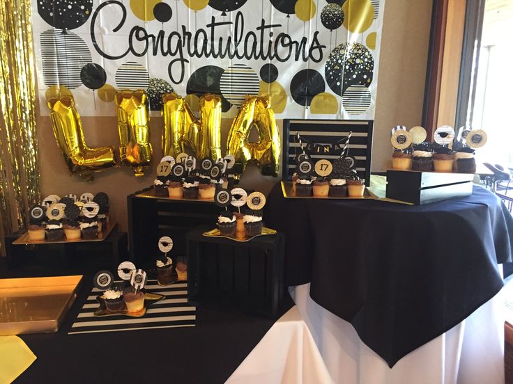 black and gold decorations are on display in front of the party table at a celebration