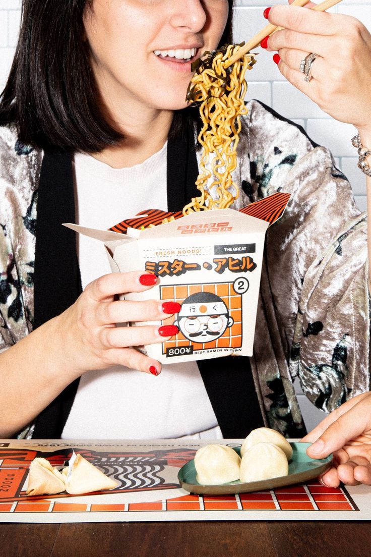 a woman eating noodles with chopsticks at a table