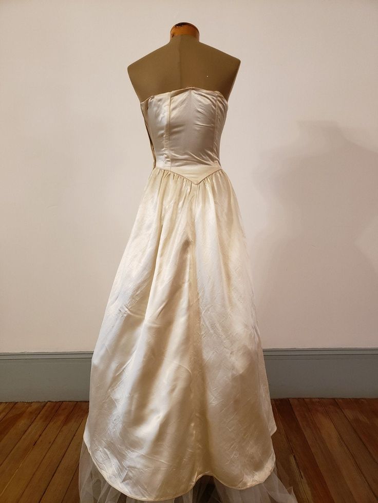 "1950s, 34\"bust,wedding ensemble consists of gown and coat of egg shell white rayon slipper satin. Gown has crystal beading at bosom, in a bow motif. Bodice of gown is strapless, with stays sewn into the interior of bodice, bodice comes to a point at waist. Skirt is full, fuller in back, and a bit longer in back than front. Coat has rounded lapels, buttons at mid section with 5 round satin buttons. Skirt of coat is floor length in front, with a cathedral length train in back. Faux pockets are a Cream Ball Gown For Debutante Ball, Regency Style Ball Gown For Vintage Events, Vintage White Evening Dress For Wedding, Classic Silk Evening Dress For Weddings, Silk Evening Dress With Lined Bodice For Wedding, Vintage White Wedding Evening Dress, Silk Wedding Evening Dress With Lined Bodice, Cream Ball Gown For Formal Occasions, Cream Ball Gown For Evening