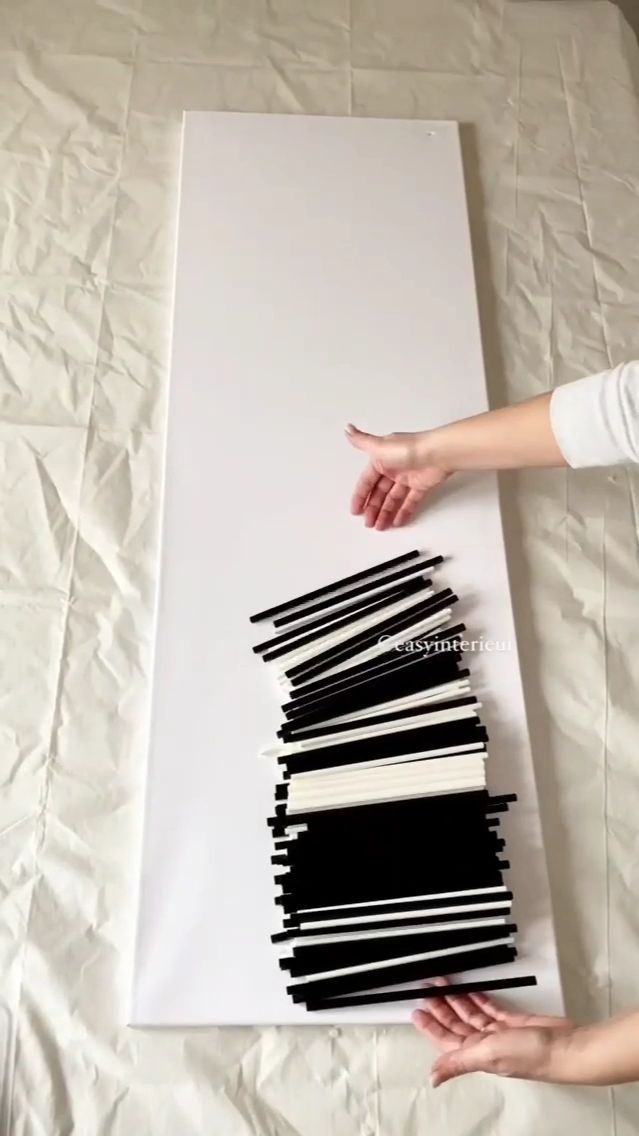 two hands reaching for black and white pieces of fabric on a sheet of paper that has been folded over