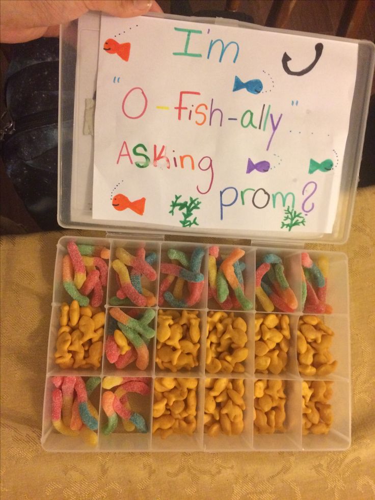 a plastic container filled with lots of different types of fish food next to a sign that says i'm o - fish - ally asking prom