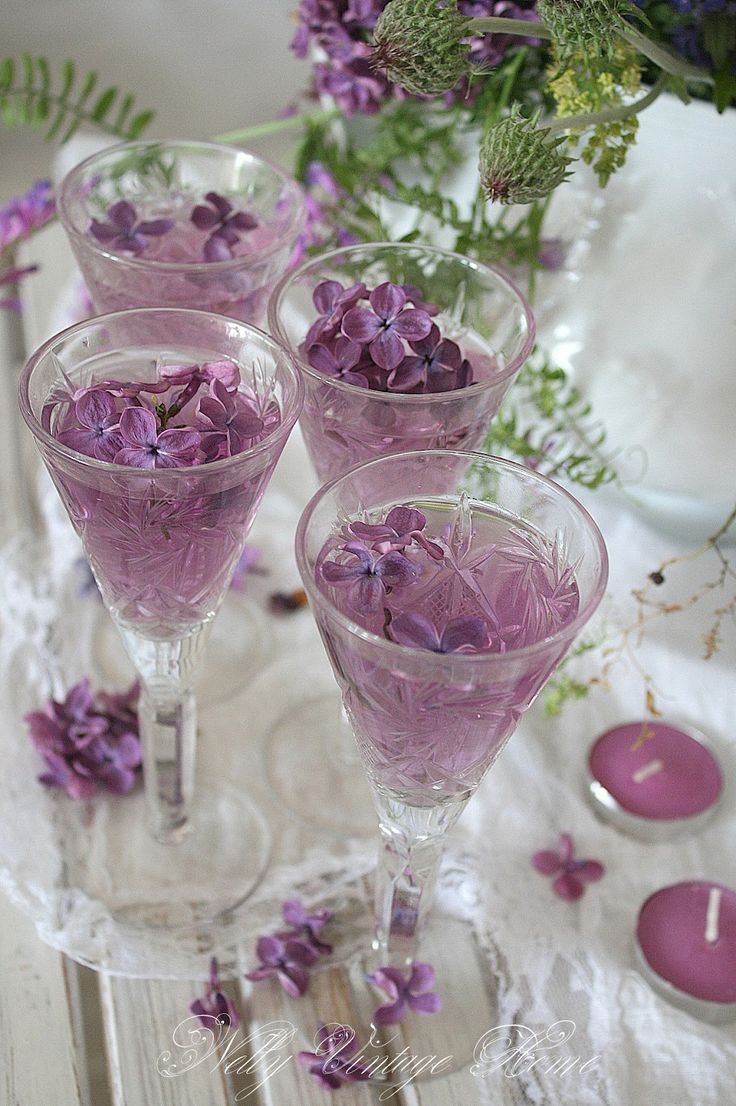 three wine glasses filled with purple flowers on a table