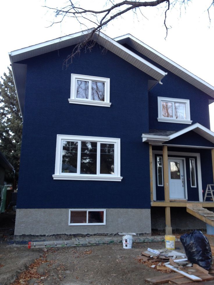 a blue house with white windows and sidings on the front porch is under construction