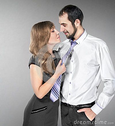 a man and woman are posing for a photo together in front of a gray background