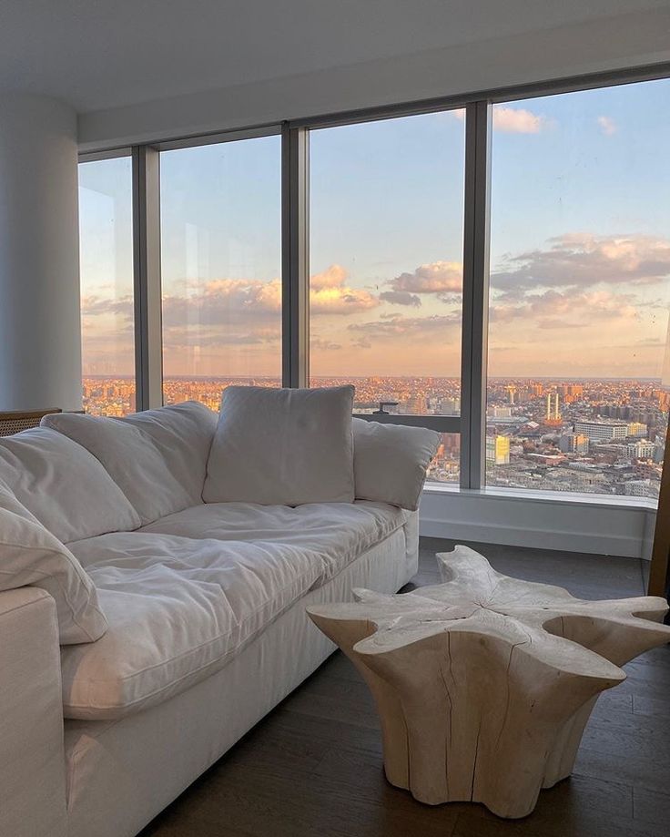 a living room with large windows and a white couch in front of the floor to ceiling windows