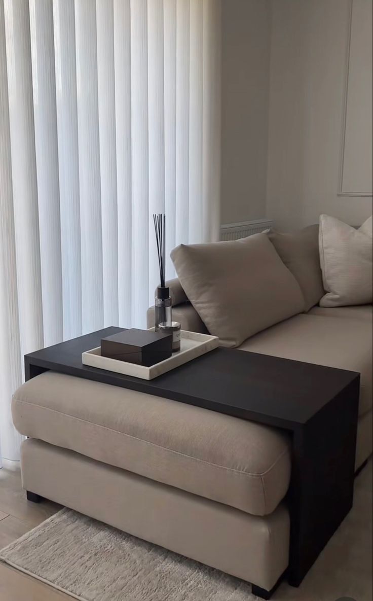 a living room with a couch, coffee table and white curtains