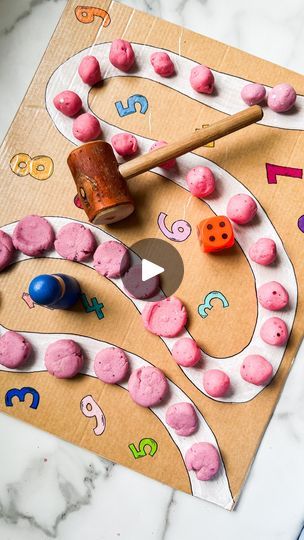 a play dough board with numbers and dices on it, next to a rolling pin