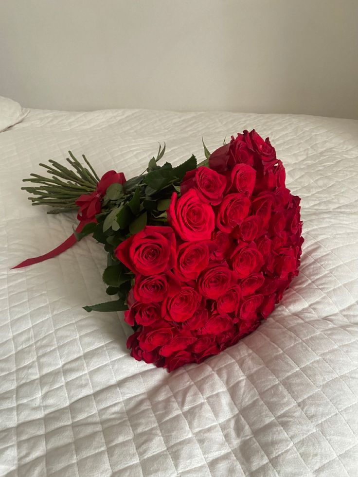 a bouquet of red roses on a white bed