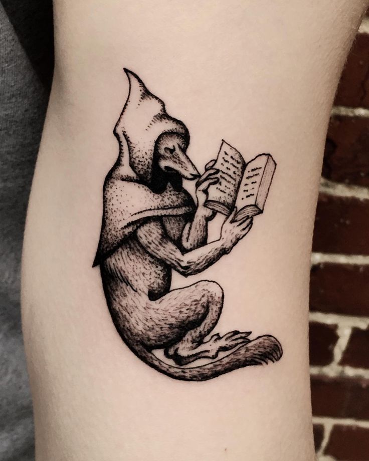 a black and white tattoo of a monkey reading a book