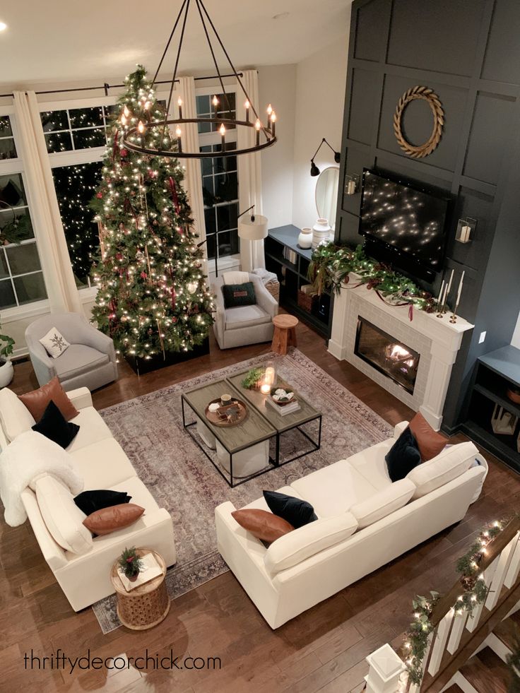 a living room filled with white furniture and a christmas tree in the middle of it