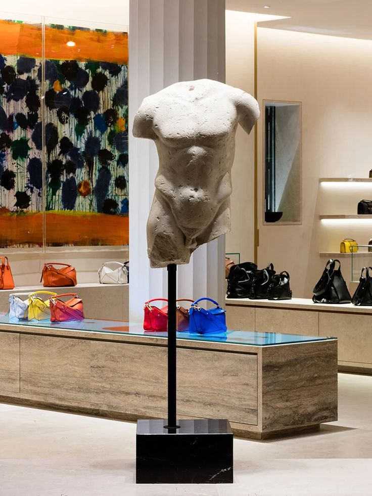 a white sculpture is in the middle of a room with many handbags and purses