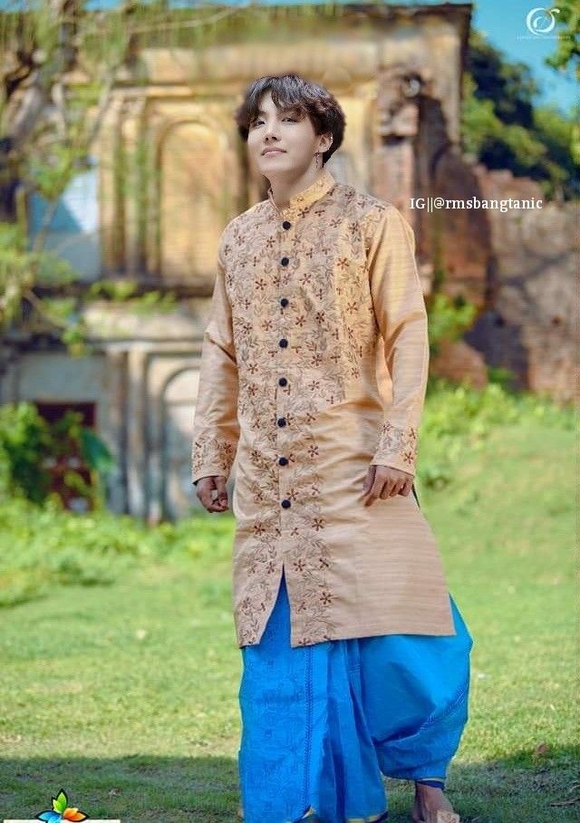 a man standing in the grass wearing a tan and blue outfit