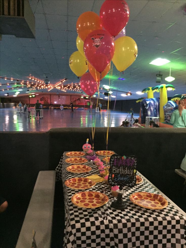 a table with pizza and balloons on it at a birthday party in an indoor setting