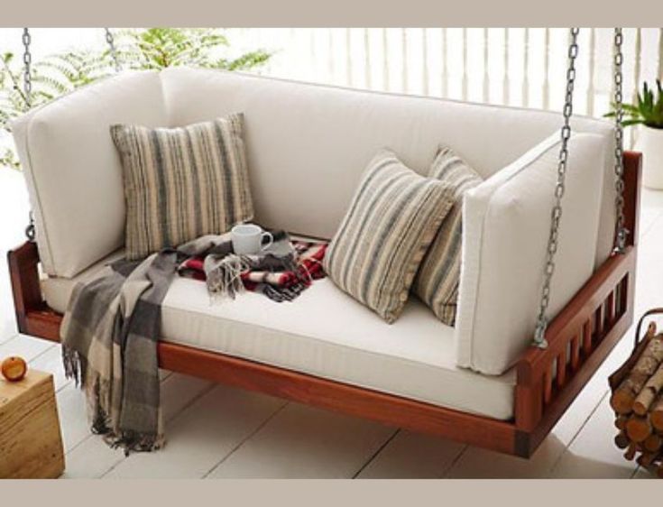 a porch swing with pillows and blankets on it