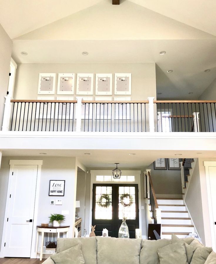 a living room filled with furniture under a wooden cross beam above a stair case in front of a white door