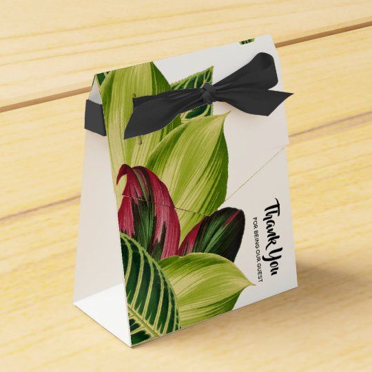 a small gift bag with a black bow on the front and green leaves on the back