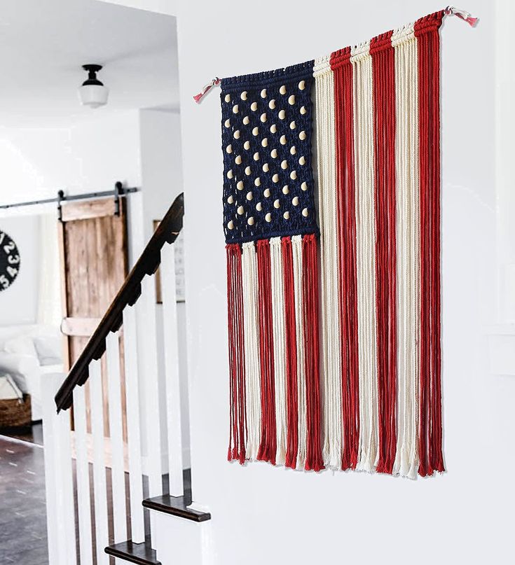 an american flag hanging on the wall next to a stair case with a clock in the background