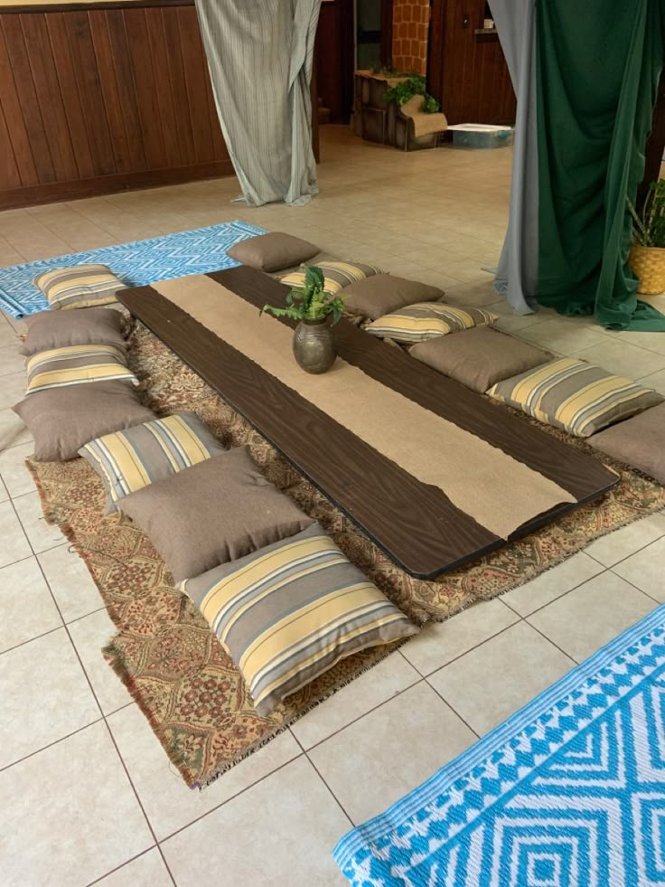 a large rug is on the floor in front of some curtains and potted plants