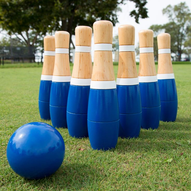 blue and white plastic bowling pins lined up next to a blue ball on the grass