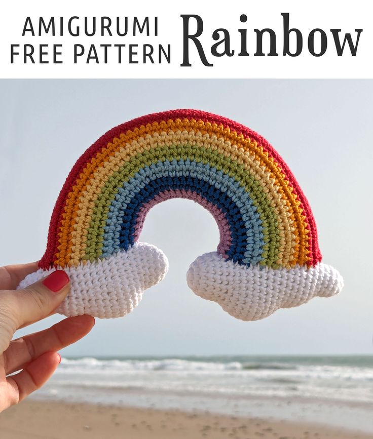 someone holding up a crocheted rainbow on the beach with text overlay that reads, amigurum pattern rainbow