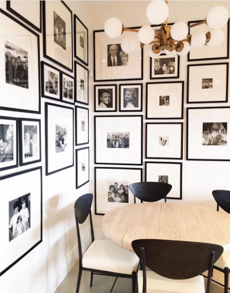 a dining room table and chairs in front of a wall full of black and white pictures