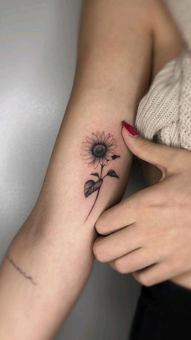 a woman's arm with a small sunflower tattoo on it