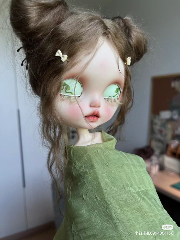 a close up of a doll with long brown hair and green eyes, wearing a green dress